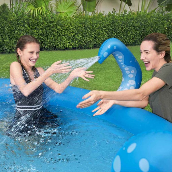 Aufblasbarer Pool mit integriertem Tentakel-Wassersprüher im Garten, ein Mädchen spielt im Wasser und eine Frau schaut zu.
