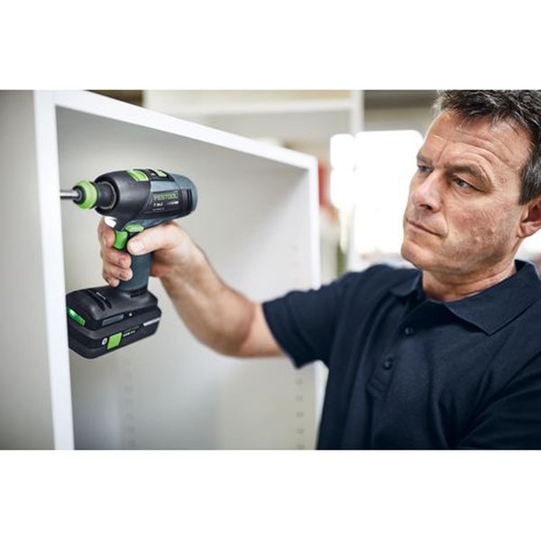 Ein Handwerker nutzt einen akkubetriebenen Festool Schrauber, um eine Schraube in ein weißes Möbelstück aus Holz zu drehen.