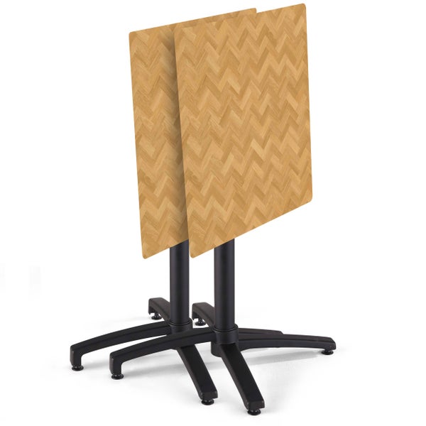 Zwei quadratische Bistrotische mit Tischplatten in Holzoptik mit Fischgrätmuster und schwarzen Metall-Säulengestellen, hochgeklappt.