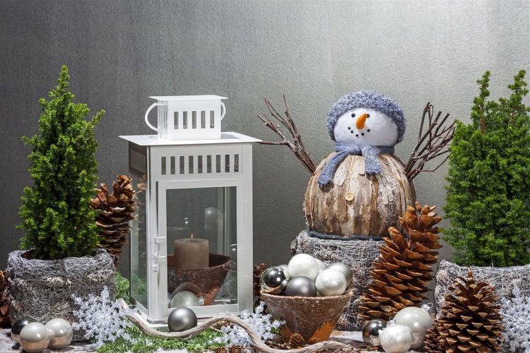 Weihnachtliche Dekoration mit Laterne, Schneemann, Bäumen und Tannenzapfen
