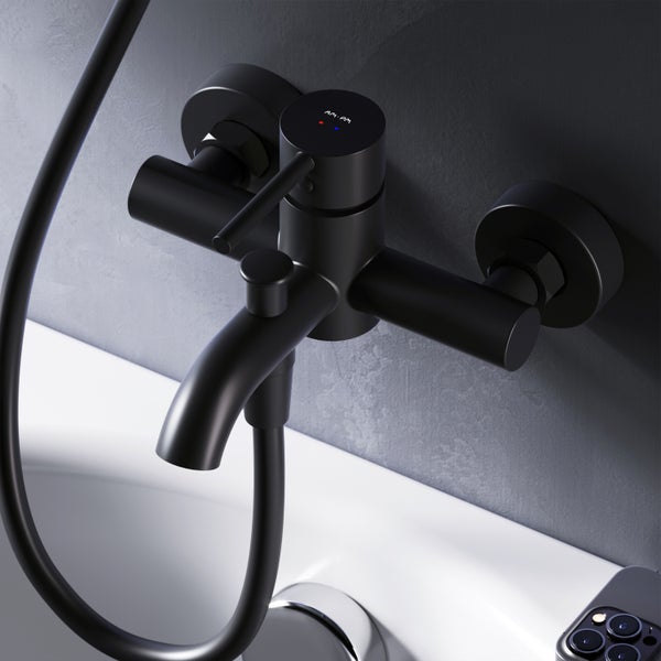 Schwarze Badewannenarmatur mit Brauseschlauch an einer Wand