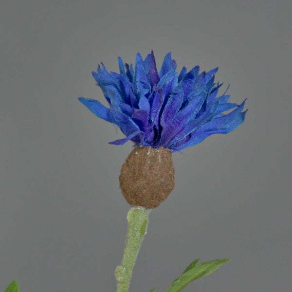 Künstlicher Kornblumen-Zweig mit blauen Blüten und grünen Blättern.