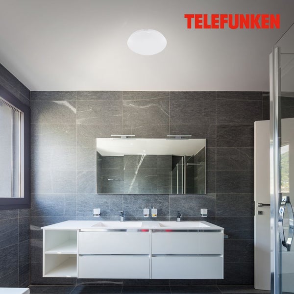 Modernes Badezimmer mit runder LED-Deckenleuchte, weißem Doppelwaschtisch und Wandfliesen in Natursteinoptik. Telefunken Logo.