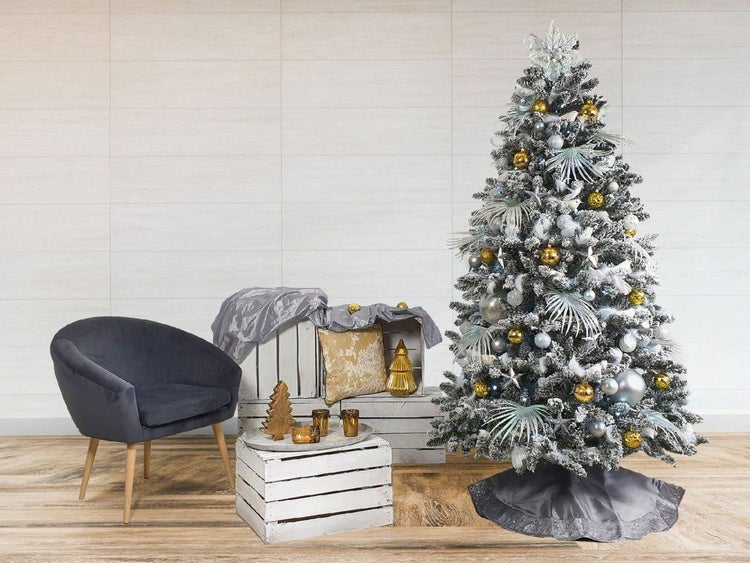 Weihnachtlich geschmückter, künstlicher Tannenbaum mit Dekoration und Sessel in einer wohnlichen, weihnachtlichen Raumgestaltung.