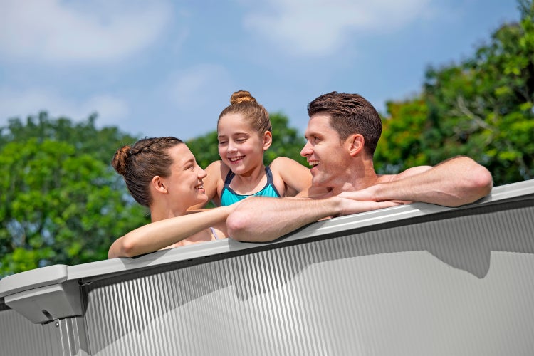 Familie in einem hellen Garten in einem Aufstellpool mit Stahlwand.