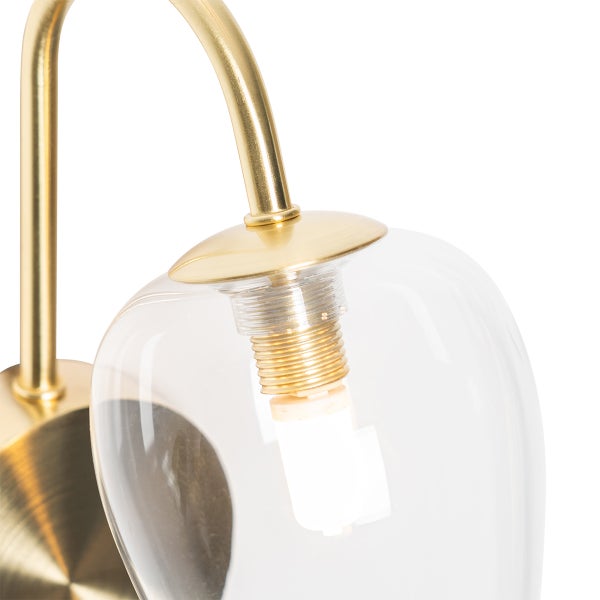 Detailaufnahme einer goldenen Lampe mit klarem Glasschirm