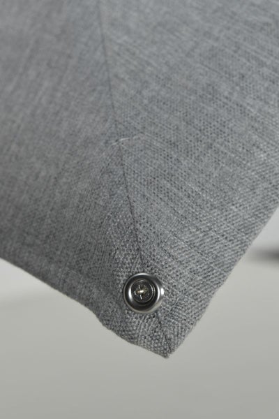 Detailaufnahme eines grauen Webstoffes mit einer sichtbaren Metallschraube.