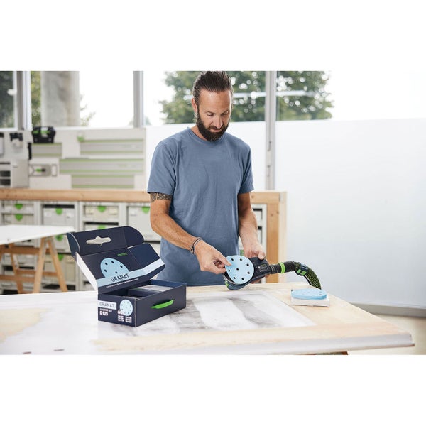 Mann befestigt Schleifpapier auf einem Festool Exzenterschleifer mit Granat Schleifscheiben Starter Set.