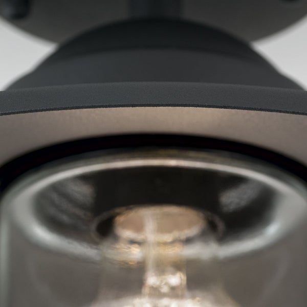 Detailaufnahme einer schwarzen Leuchte aus Metall mit Glasschirm und Leuchtmittel.