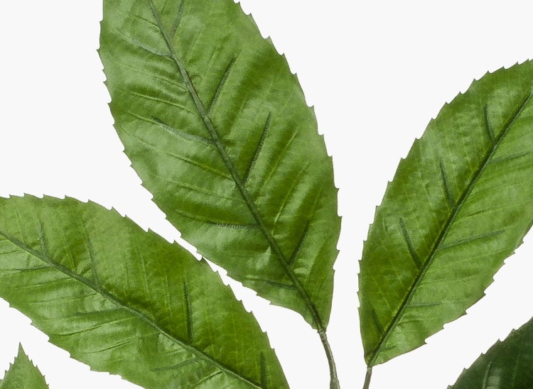 Detailaufnahme eines künstlichen grünen Zweigs mit Blättern und strukturierter Stieloberfläche.