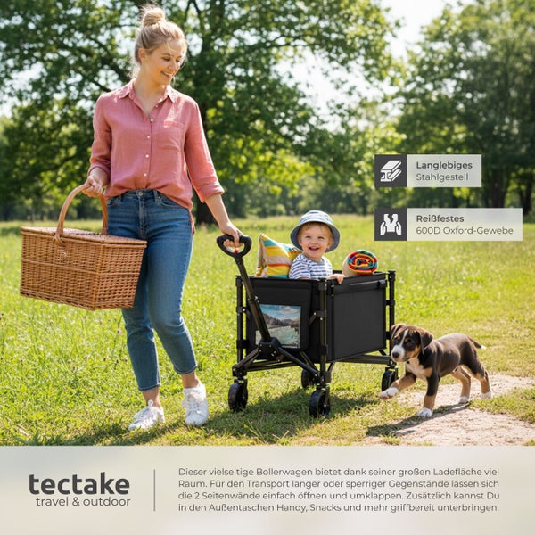 Frau zieht Bollerwagen mit Kind, Picknickkorb und Hund im Freien.