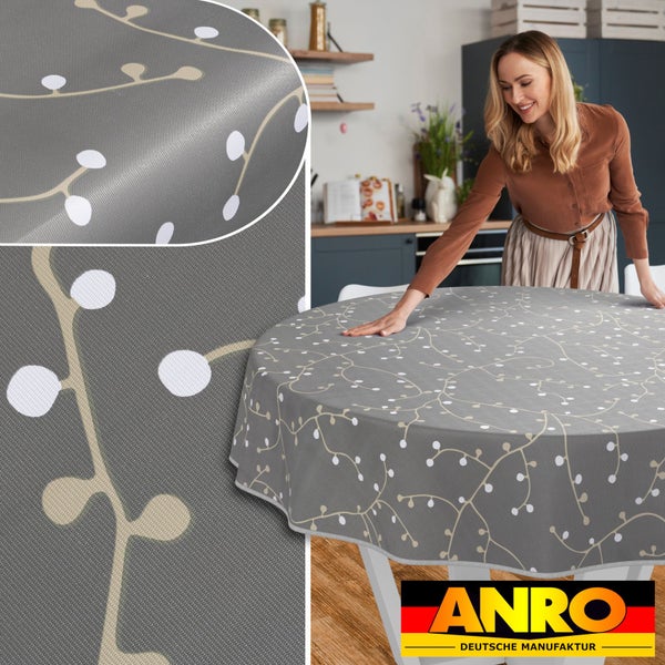 Runde Tischdecke mit Muster auf einem Tisch, im Hintergrund eine Frau in einer Küche, Anro Deutsche Manufaktur Logo