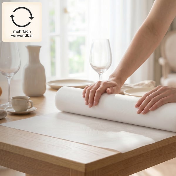 Hände rollen eine weiße strukturierte Mehrweg-Tischauflage auf einem Holztisch aus. Heller Raum mit Gedeck. Symbol für mehrfache Verwendbarkeit.
