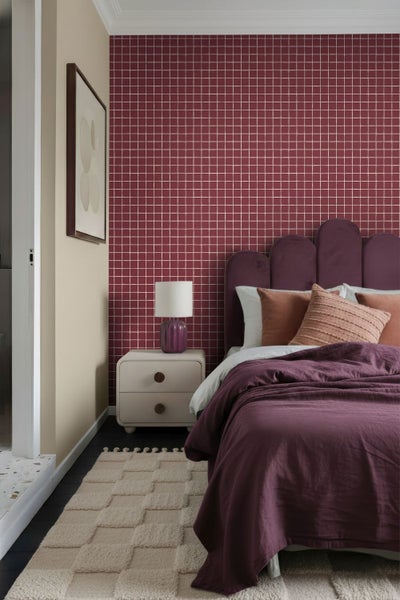 Schlafzimmer mit Bett, Nachttisch und Wandtapete im Rasterdesign