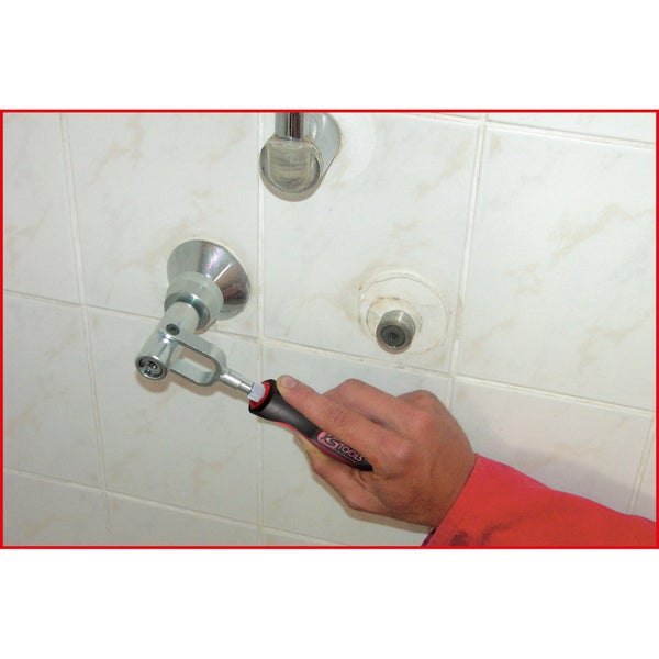 Ein Handwerker montiert mit einem Spezialwerkzeug eine Armatur an einer Badezimmerwand.