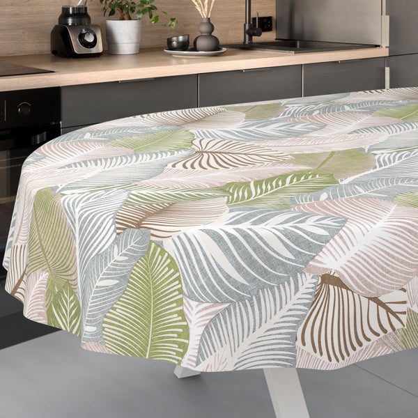 Runde Tischdecke mit großem Blättermuster in einer hellen, modernen Küche mit grauen Schränken und einer Arbeitsplatte aus Holz.