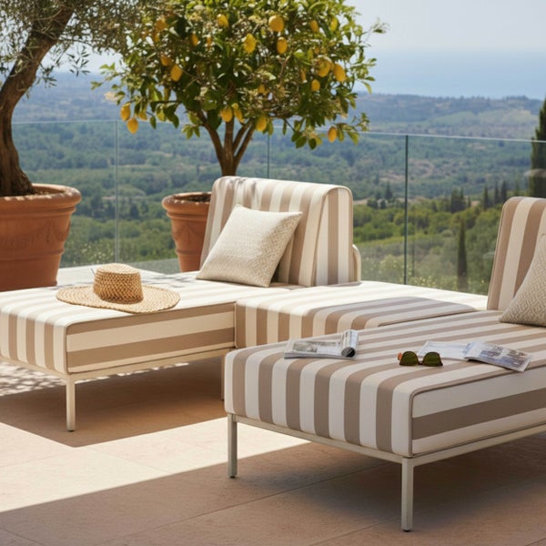 Moderne gestreifte Gartenliegen auf einer hellen Terrasse mit Blick auf eine Hügellandschaft, Dekokissen, Zitronenbaum im Tontopf.