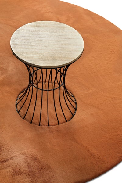 Runder Beistelltisch mit Holzplatte und schwarzem Metalldrahtgestell auf einem weichen Teppich in Felloptik.