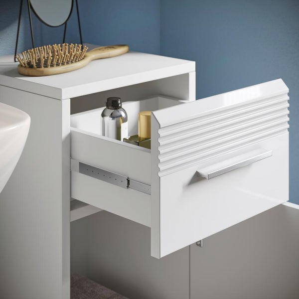 Weißer Badezimmer-Unterschrank mit geöffneter Schublade, geriffeltem Frontdesign und Metallgriff.