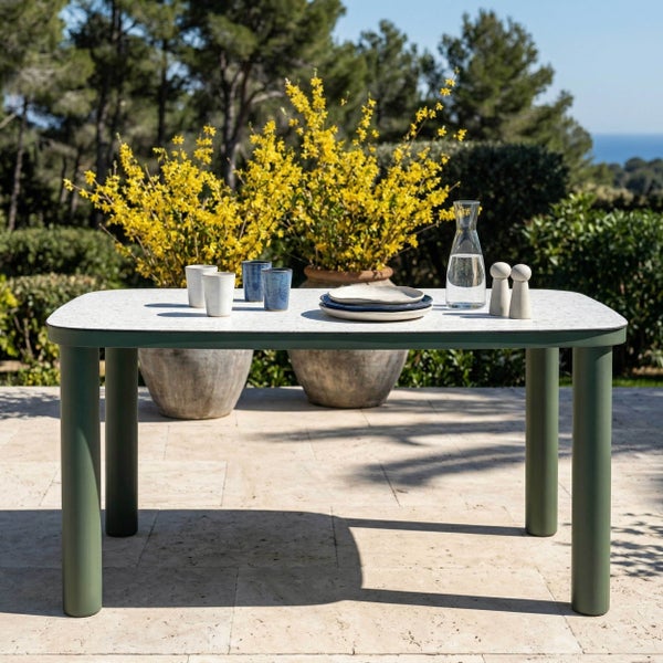 Moderner rechteckiger Gartentisch mit gesprenkelter weißer Platte und stabilen grünen Beinen auf einer hellen Terrasse.