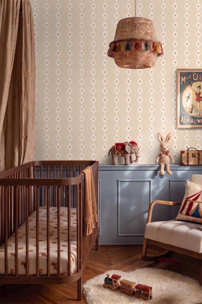Einrichtung eines Kinderzimmers mit Babybett, Schaukelstuhl und einer Tapete mit Rautenmuster und kleinen Sternen im Zirkusstil.