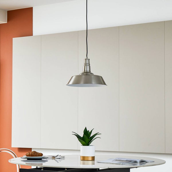 Industrielle Pendelleuchte aus Metall über einem runden Esstisch in einem hellen, modern eingerichteten Raum.