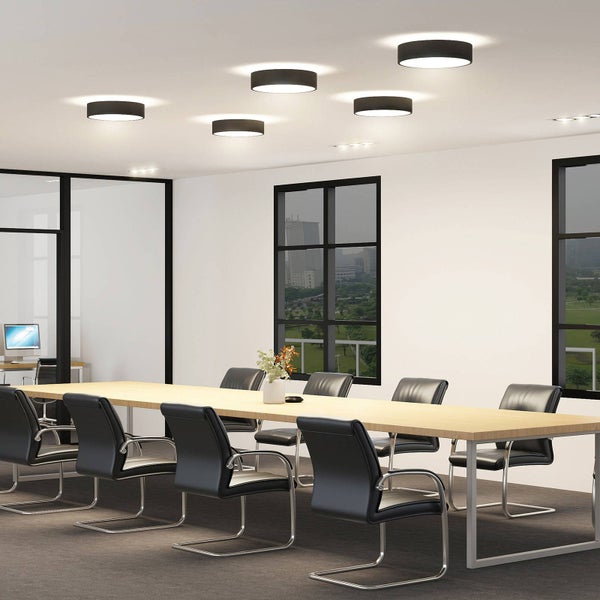 Moderner Konferenzraum mit langem Holztisch, schwarzen Stühlen und runden schwarzen LED-Deckenleuchten für helle Beleuchtung.