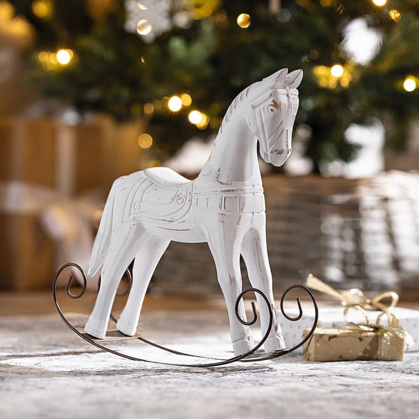 Dekoratives Schaukelpferd aus Holz mit Metallgestell vor Weihnachtsbaum und Geschenken