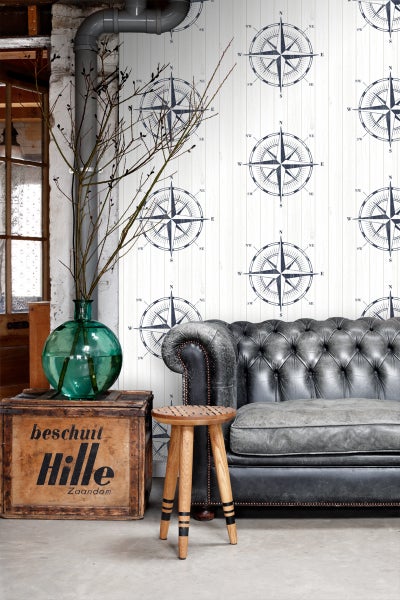 Wohnzimmer mit Kompass Tapete, Ledersofa und Holzhocker