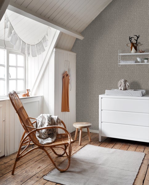 Kinderzimmer mit Wickelkommode, Rattansessel und Stricktapete für eine gemütliche Atmosphäre