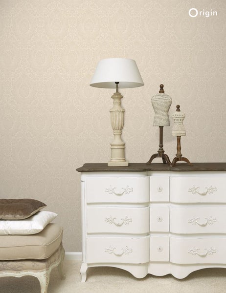 Dekoratives Zimmer mit gemusterter Tapete, Kommode, Lampe und Schneiderpuppen