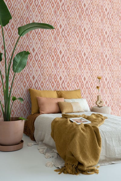 Dekoratives Schlafzimmer mit gemusterter Tapete und Zimmerpflanze im Topf.