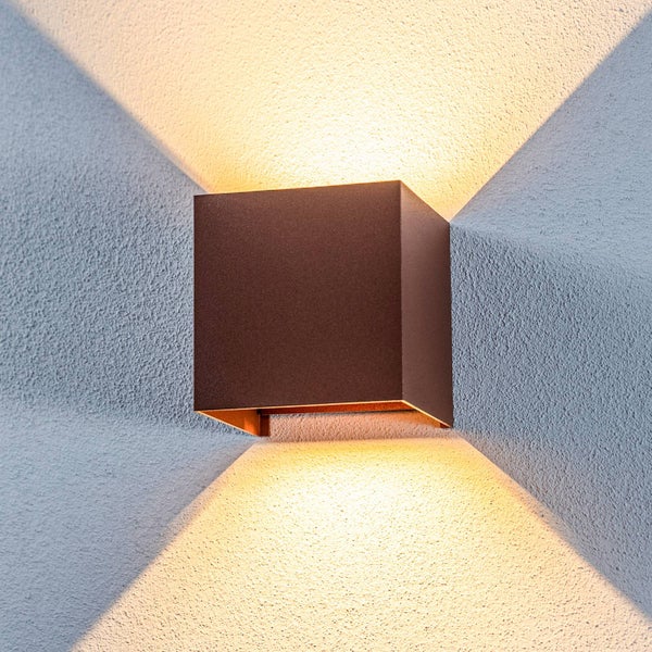 Moderne würfelförmige Außenwandleuchte mit Up-and-Down-Lichteffekt an einer strukturierten Fassade.