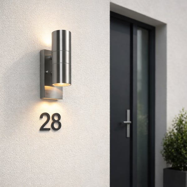 Moderne Außenwandleuchte aus Edelstahl in Zylinderform als Up-and-Downlight, montiert an einer Hauswand über der Hausnummer 28.