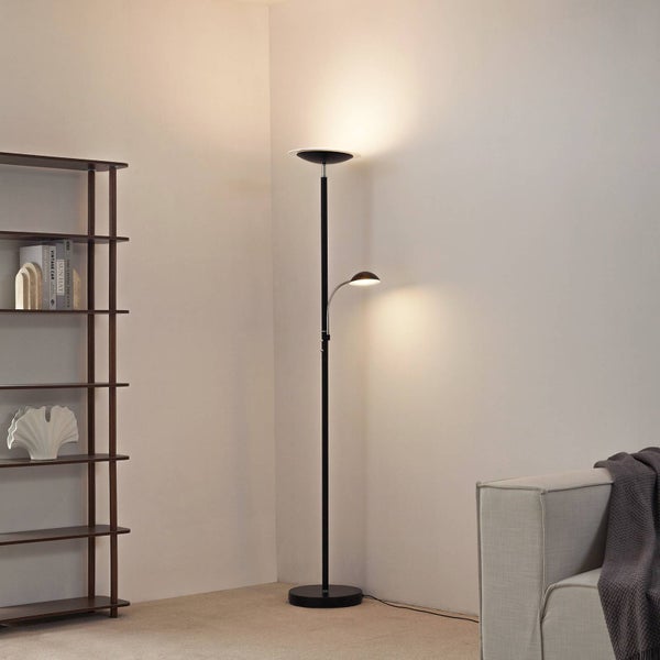 Schwarzer Deckenfluter aus Metall mit Leselampe in einem hellen, minimalistischen Wohnzimmer neben einem Standregal und Sofa.