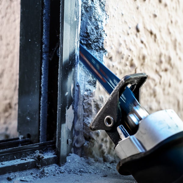 Eine Säbelsäge schneidet durch eine Wand in der Nähe eines Fensters.