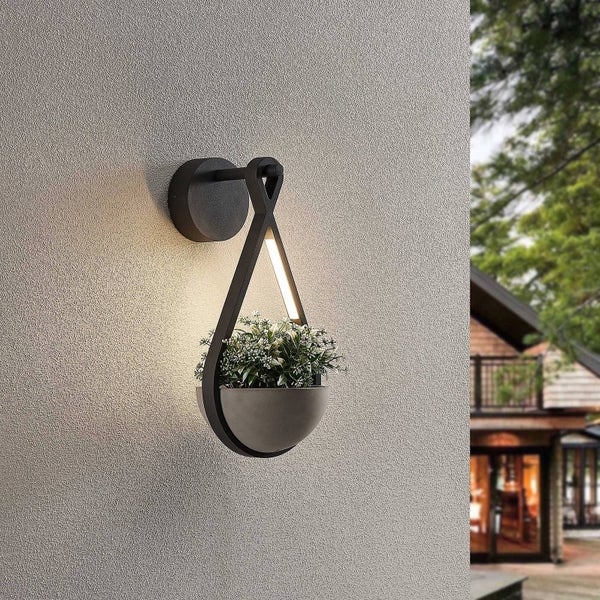 Moderne LED-Wandleuchte mit integriertem Blumentopf, tropfenförmiges Design, Rahmen aus Metall, warmes Licht auf einer strukturierten Außenwand.
