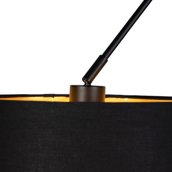 Nahaufnahme einer Lampe mit schwarzem Textilschirm und goldfarbener Innenseite sowie schwarzem Metallgestänge.