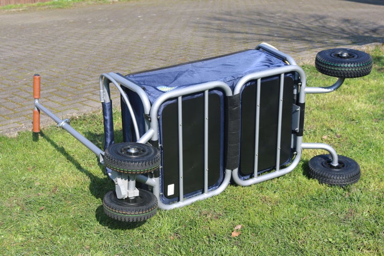 Zusammenklappbarer Bollerwagen mit Metallrahmen und gummibereiften Rädern, liegend auf einer Wiese präsentiert.