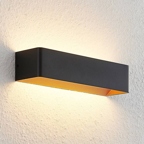 Moderne schwarze LED Wandleuchte mit goldenem Innengehäuse, Lichtaustritt nach oben und unten an einer strukturierten Wand.