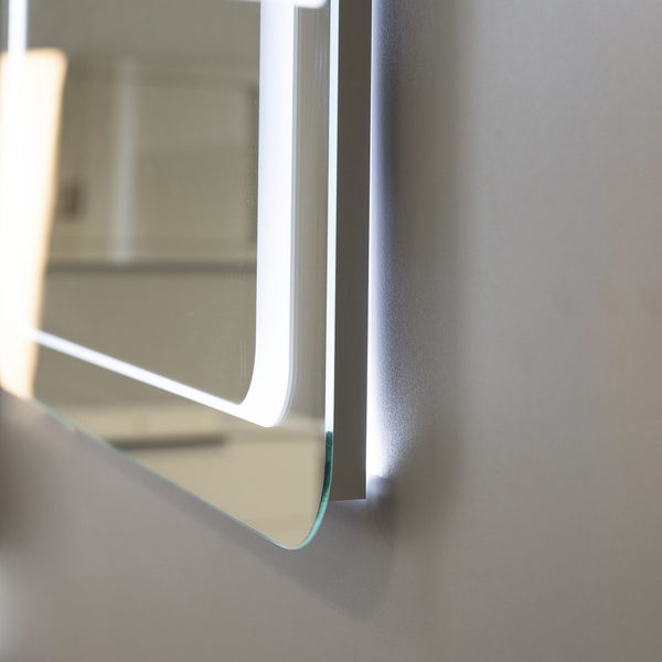 Badezimmerspiegel mit integrierter LED Beleuchtung und abgerundeten Ecken an einer Wand.