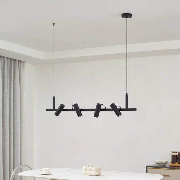 Schwarze Hängelampe mit vier Strahlern über einem Esstisch.