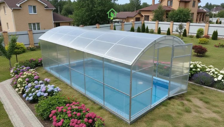 Überdachtes Gartenpool mit einer halbkreisförmigen Abdeckung aus transparentem Kunststoff in einem gepflegten Garten mit Blumenbeeten.