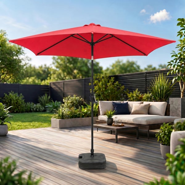 Roter Sonnenschirm mit schwarzem Mast auf einer Holzterrasse mit Lounge-Möbeln, Pflanzen und einem dunklen Zaun im Hintergrund.