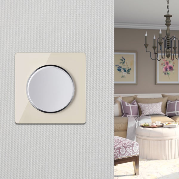 Runder Lichtschalter mit quadratischer Abdeckung an einer strukturierten Wand in einem stilvollen Wohnzimmer mit Kronleuchter.