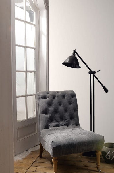 Gepolsterter Sessel neben einer Stehlampe und einer Fenstertür