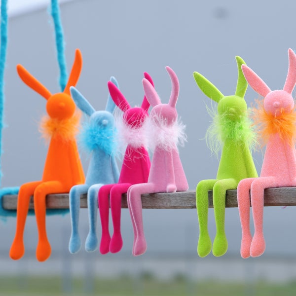 Dekorative Hasenfiguren aus Plüsch sitzen auf einem Holzbalken