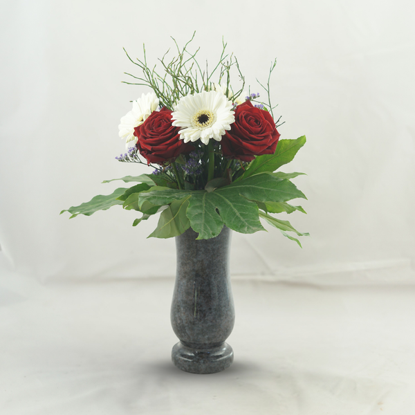 Blumenstrauß aus Rosen und Gerbera in einer Steinvase als Grabschmuck