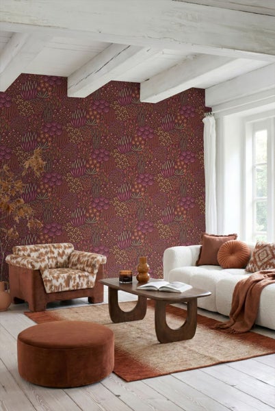 Helles Wohnzimmer mit gemusterter Vliestapete in floralem Design, weißem Sofa, gemustertem Sessel und Holzbalkendecke.