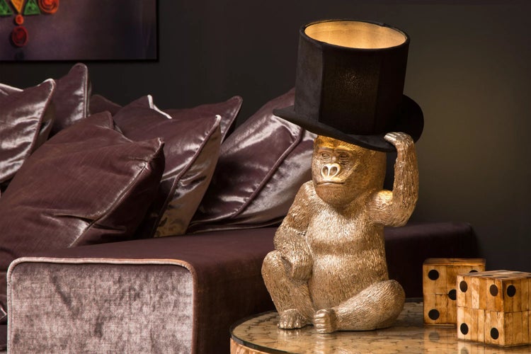 Dekorative Affenlampe mit Zylinderhut auf einem Tisch neben einem Sofa.